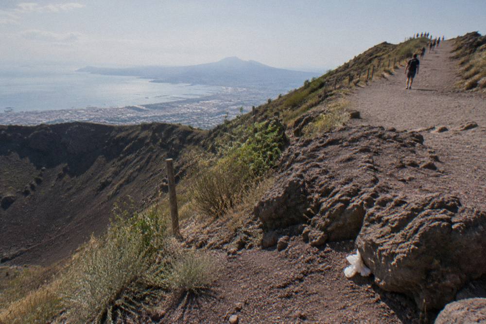 The wide gravel path climbing toward the crater rim of Vesuvius with the Bay of Naples below