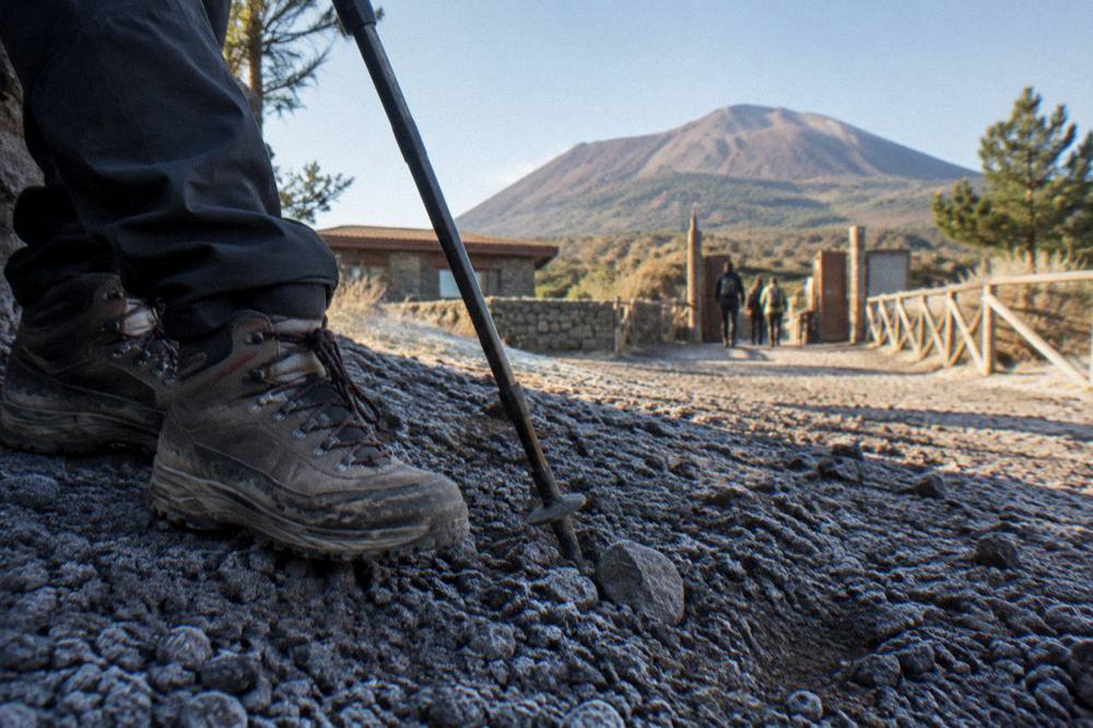 Hiking boots and a walking pole resting on volcanic gravel beside the Vesuvius trail