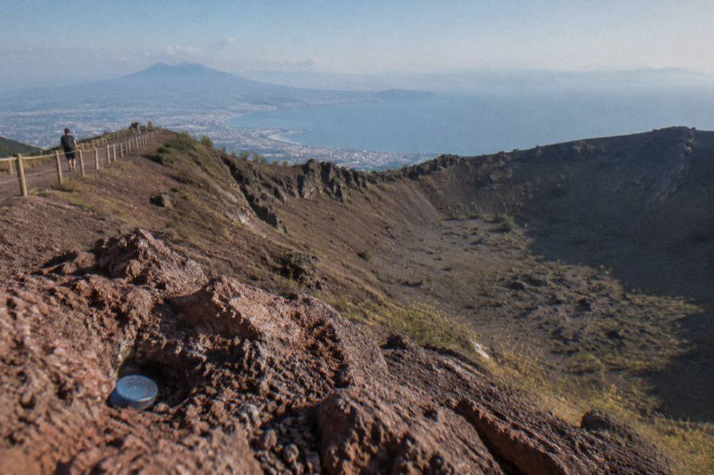The wide elliptical crater of Vesuvius seen from the rim path with the Bay of Naples in the distance