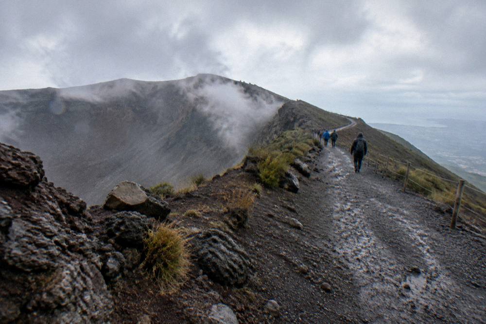 The gravel crater trail of Vesuvius rising across grey volcanic ash with the rim ahead under an open sky