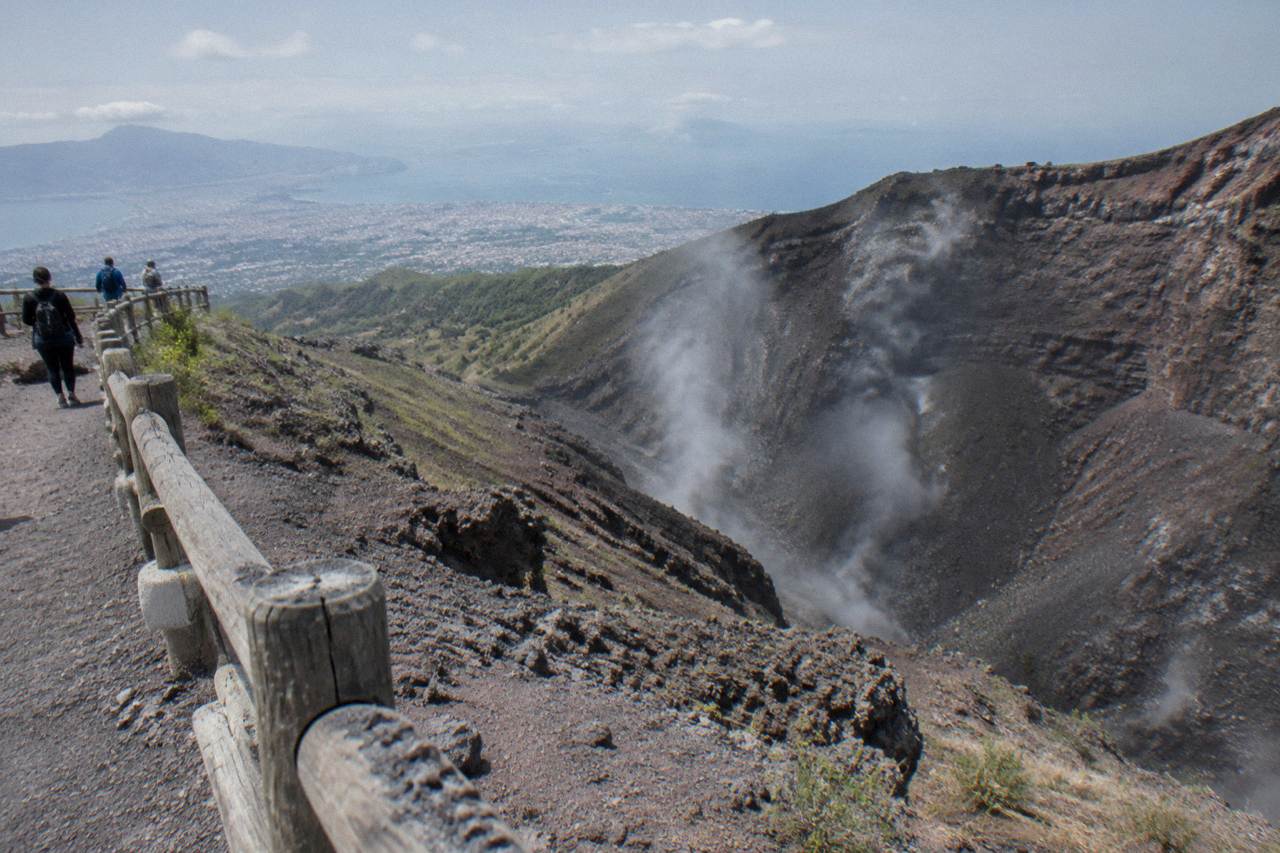 The elliptical crater of Mount Vesuvius seen from the rim with fumarole steam on the inner walls