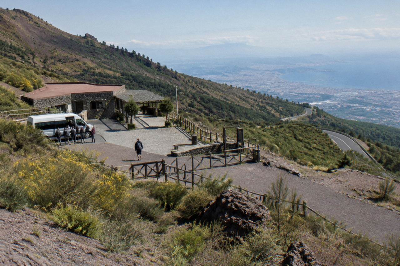 Volcanic slopes of Mount Vesuvius with a winding access road and the Bay of Naples in the distance