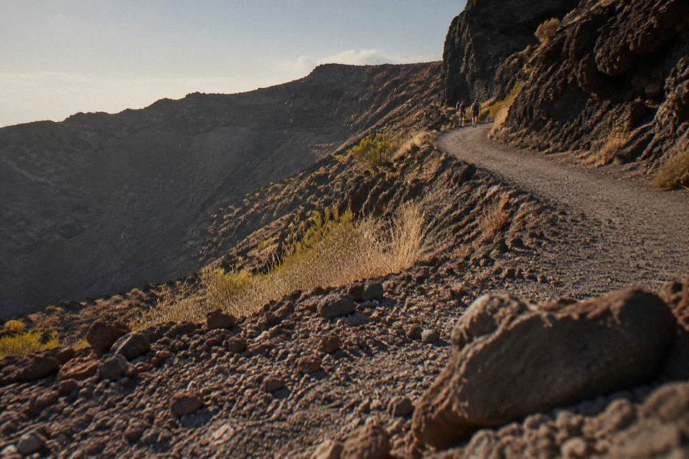 Hikers on the switchback crater path beneath dark volcanic rock