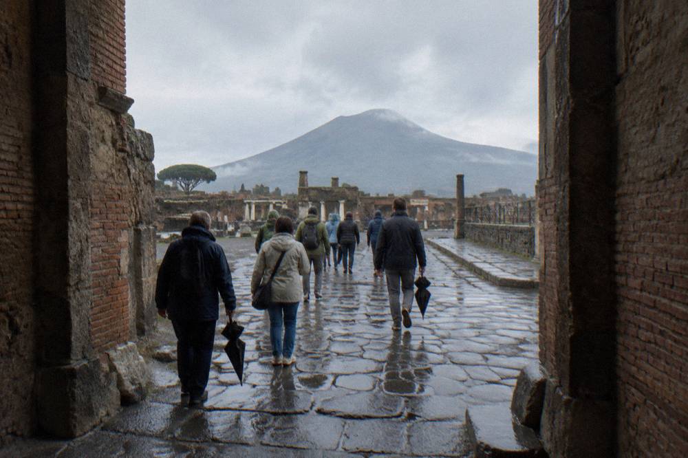 A guided tour group walking together through the Pompeii ruins toward waiting transport
