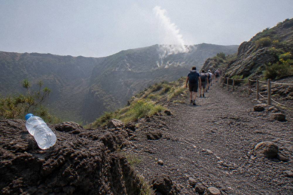Tour group walking the gravel crater path at Mount Vesuvius with steam vents on the far rim