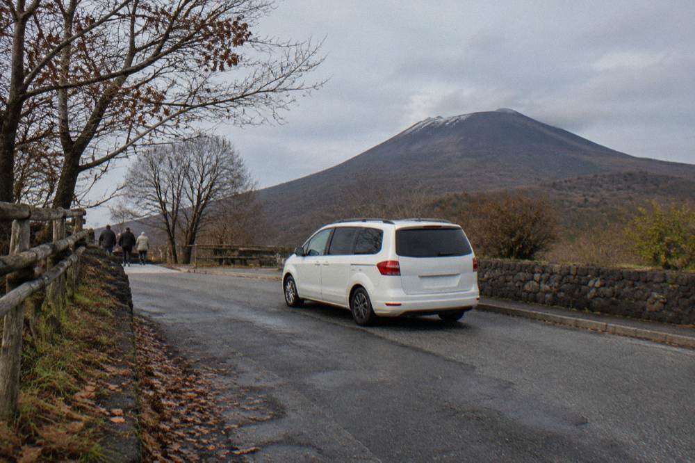 Private minivan parked on a narrow road below the wooded slopes of Mount Vesuvius