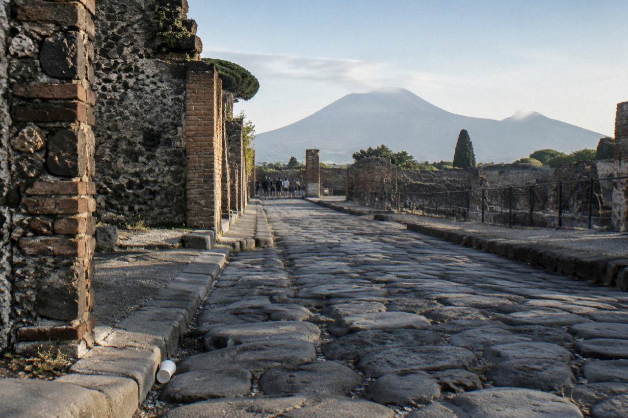 Stone ruins of an ancient Roman street under Mount Vesuvius on the horizon