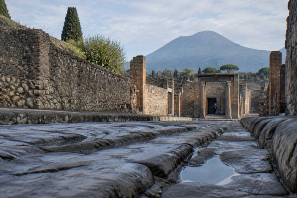 Stone-paved Roman street in Pompeii with worn cart ruts under morning light