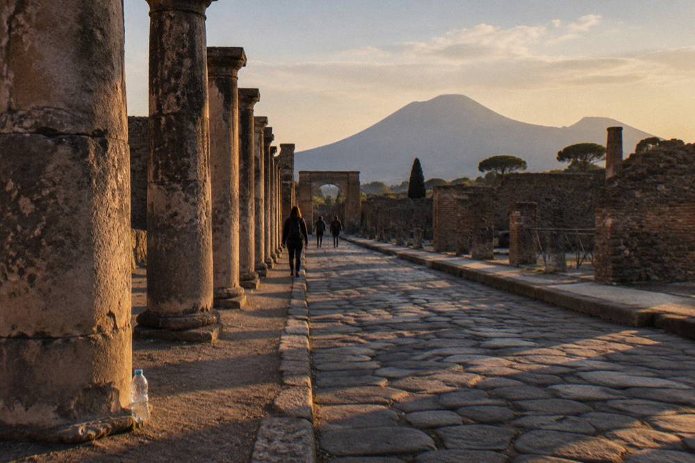 A row of stone columns along an excavated street in Pompeii under warm afternoon light.
