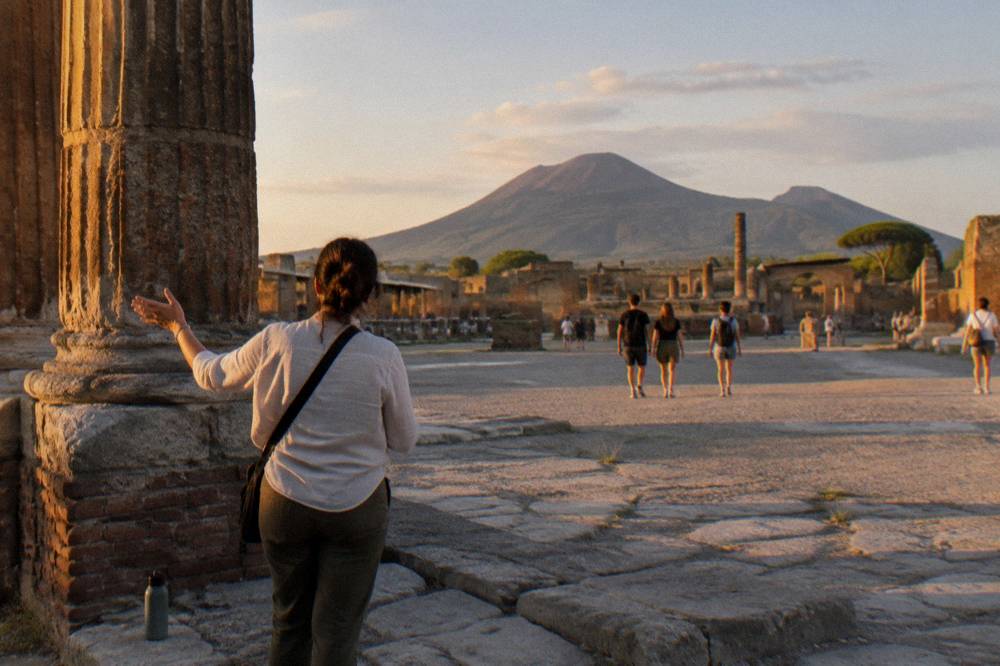 Guided group walking among the stone ruins of Pompeii under a clear sky