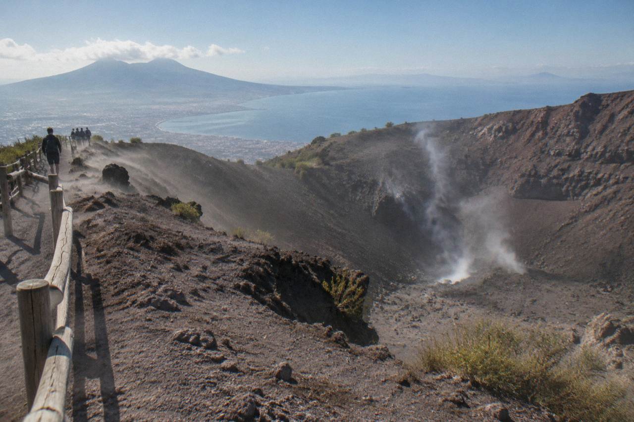 The crater rim of Mount Vesuvius under a wide sky above the Bay of Naples