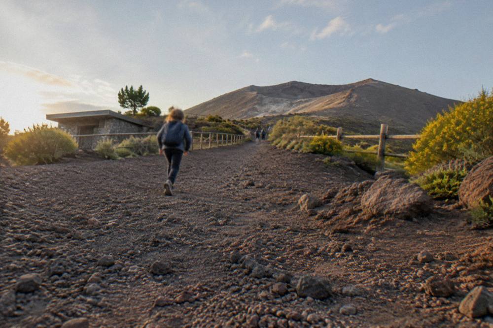 A gravel volcanic path rising gently toward a crater rim under morning light