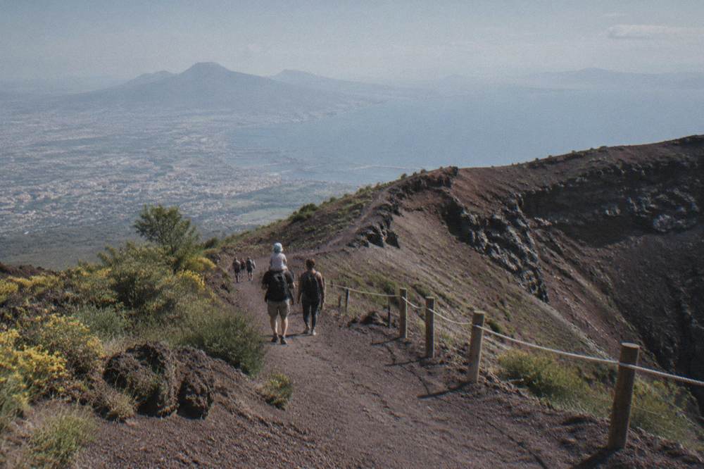 A family walking a gravel crater path with the bay spread out below