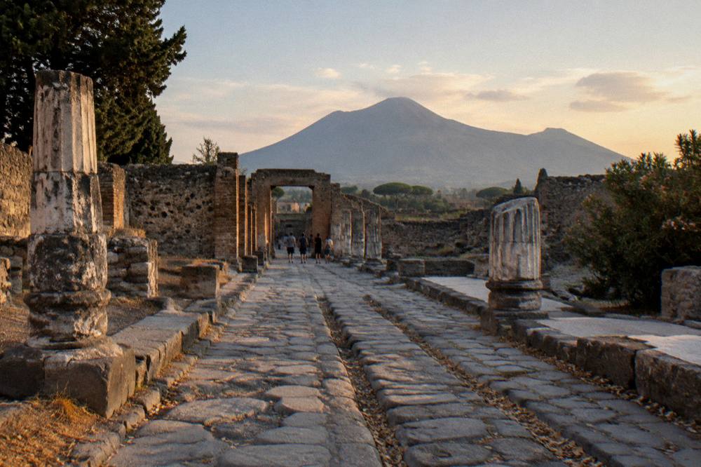 Ancient stone streets of Pompeii with the volcano rising behind the ruins