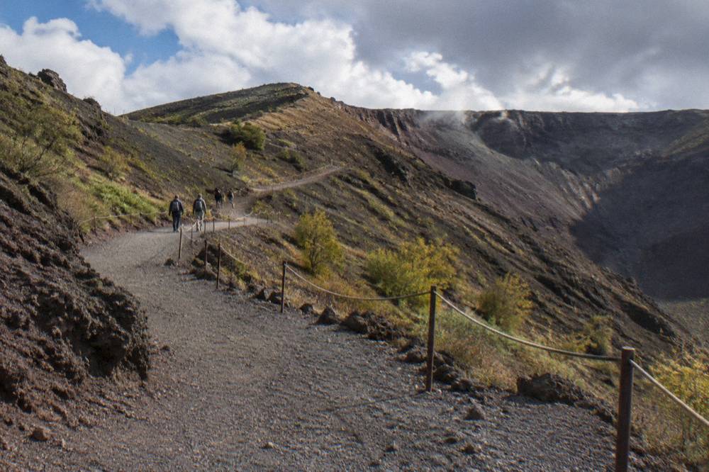 A wide gravel path zigzagging up the ash slopes toward the Vesuvius crater rim