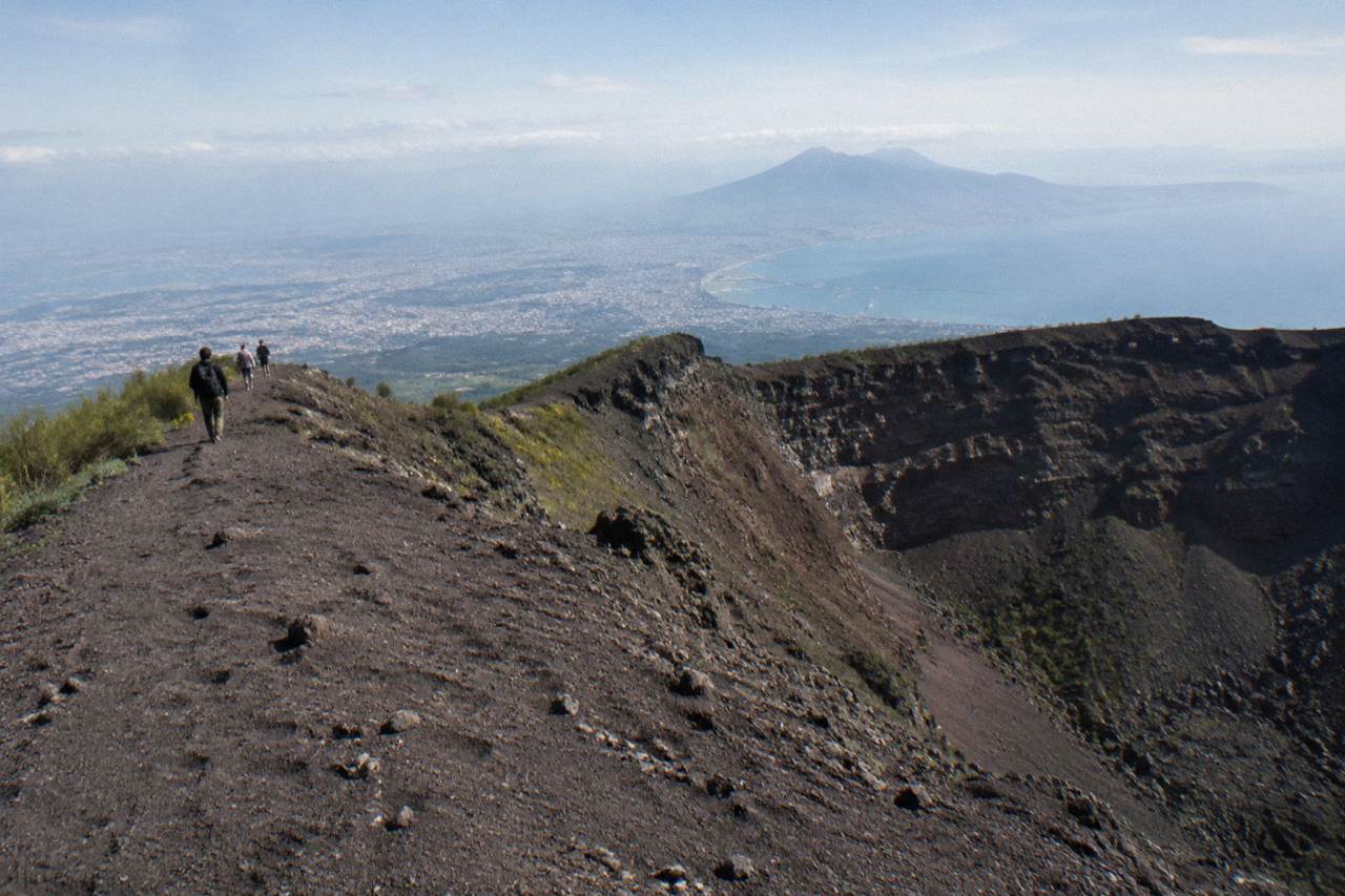 The Gran Cono crater rim of Vesuvius under a wide sky with the Bay of Naples haze below