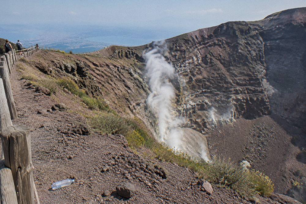 The Vesuvius crater interior with fumarole smoke on the inner walls under bright sky