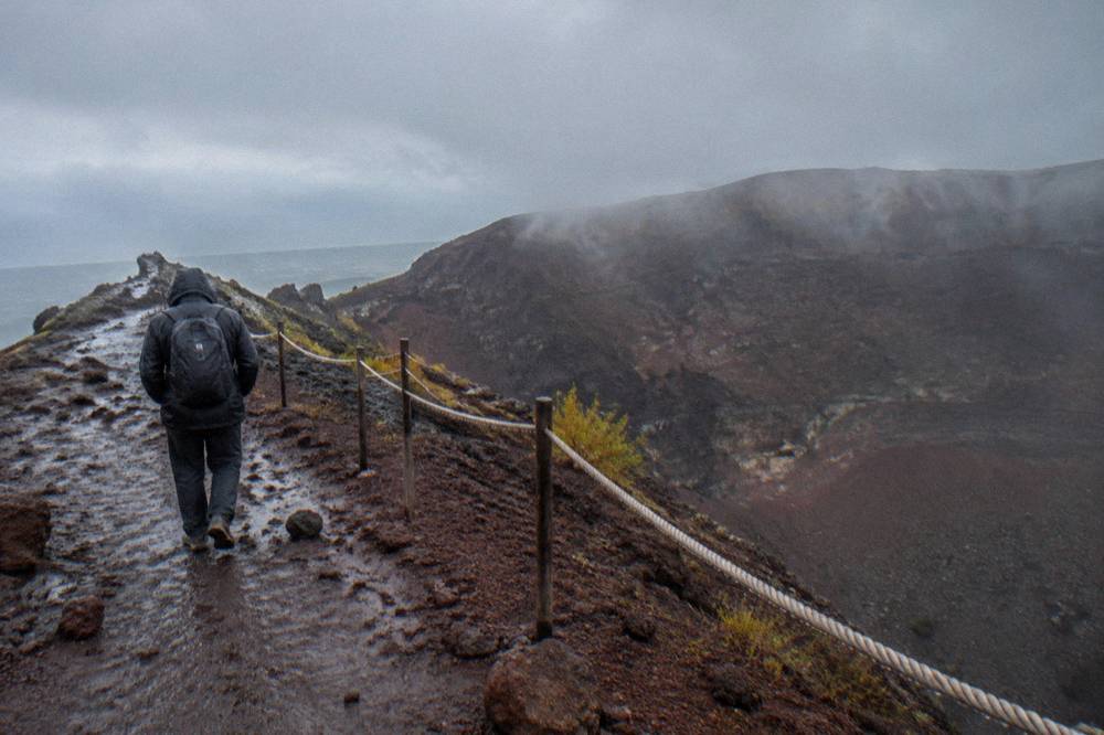 Walker in a windproof jacket on the exposed Vesuvius crater ridge in cool weather