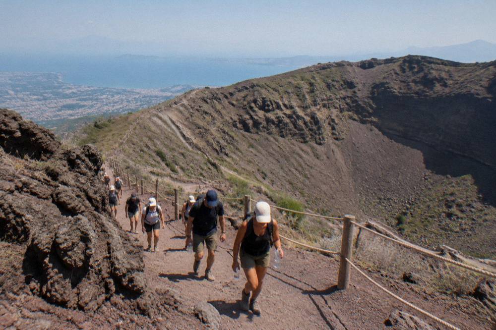 Tour group in caps and daypacks walking together on the wide Vesuvius track
