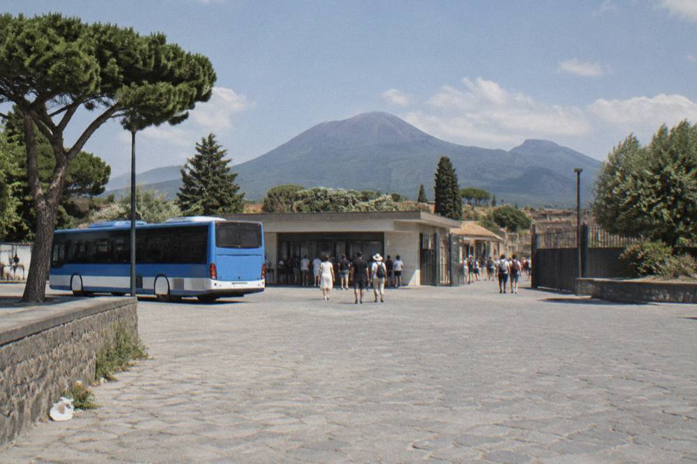 The excavated stone street of Pompeii with the green slopes of Vesuvius rising directly behind the ruins