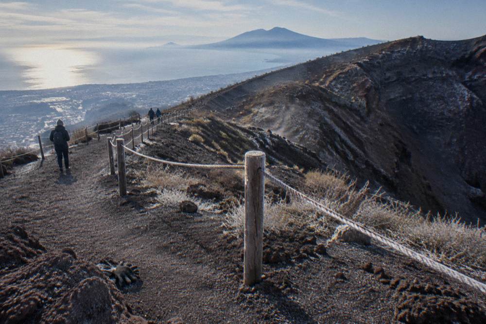 The broad gravel crater trail zigzagging up volcanic ash toward the rim with the bay below