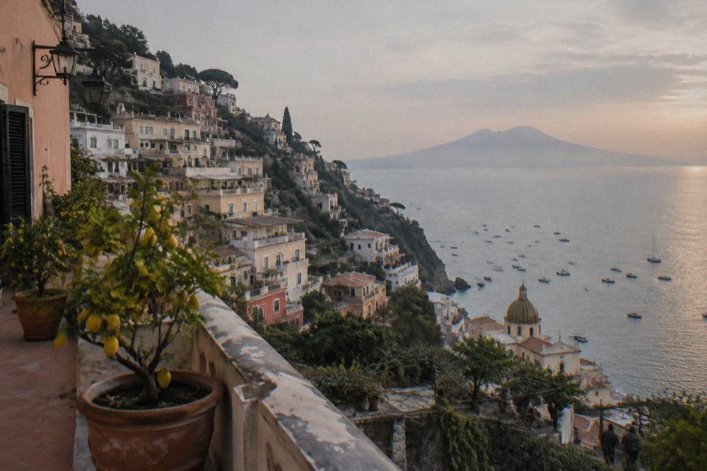 Cliffside town above a bay with the distant shape of Vesuvius on the horizon