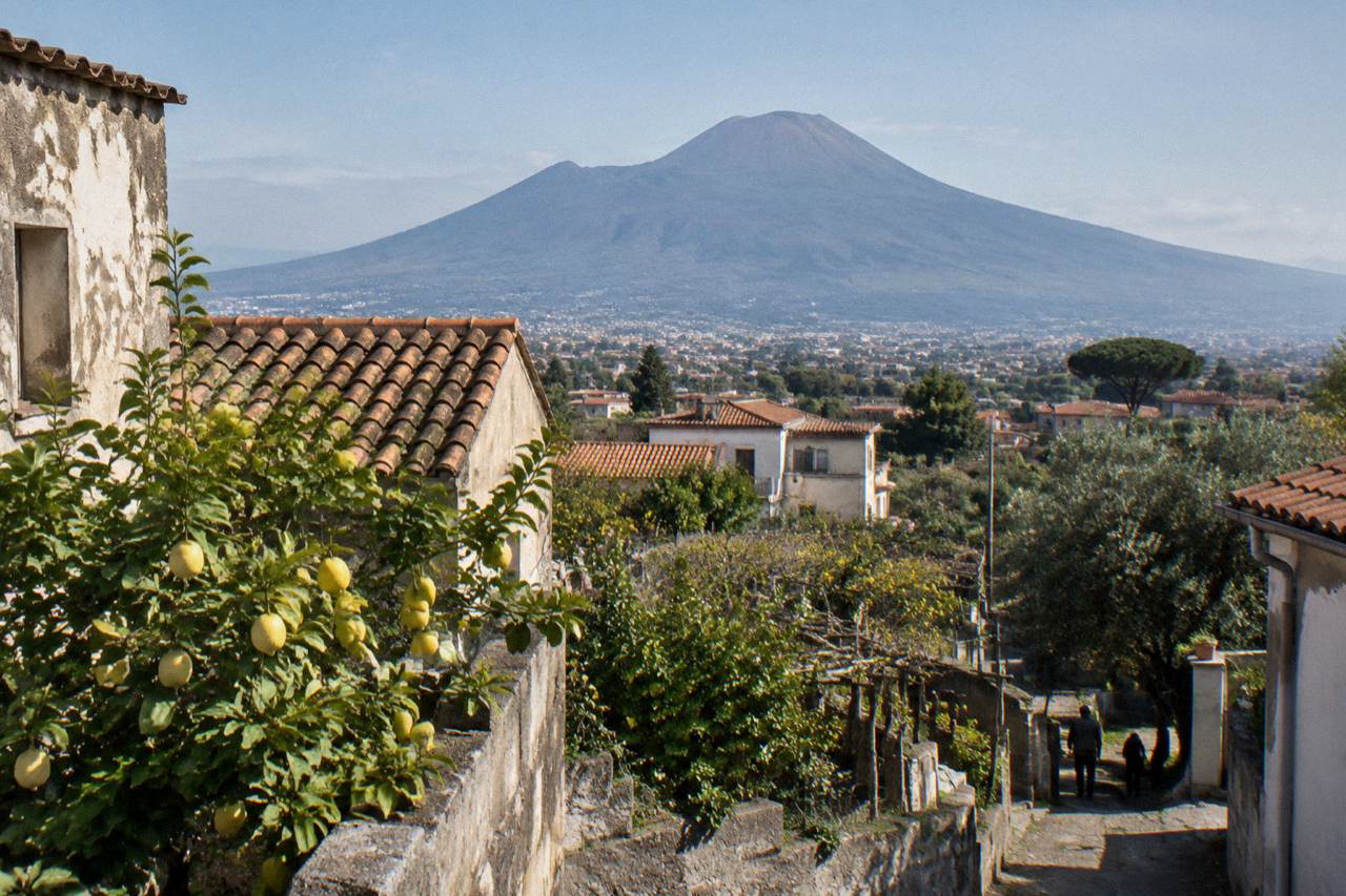View across rooftops toward the cone of Vesuvius under a clear sky at midday